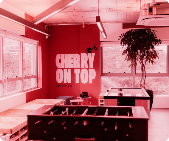 Foto em tons de vermelho da sala de laser na i-Cherry. Em uma parede ao fundo se lê cherry on top.